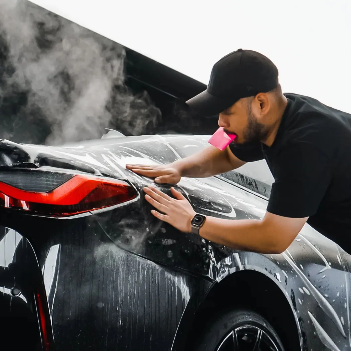 Shabz working over the rear quarter of a black car during a detail